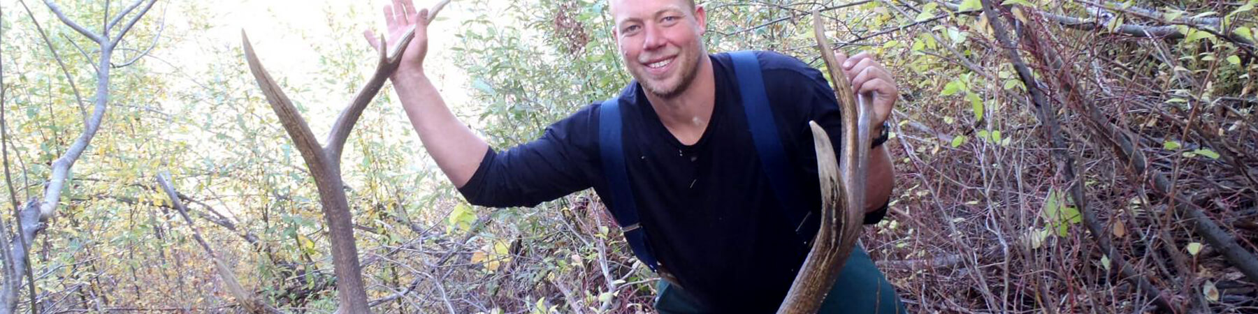 Man posing behind Elk rack