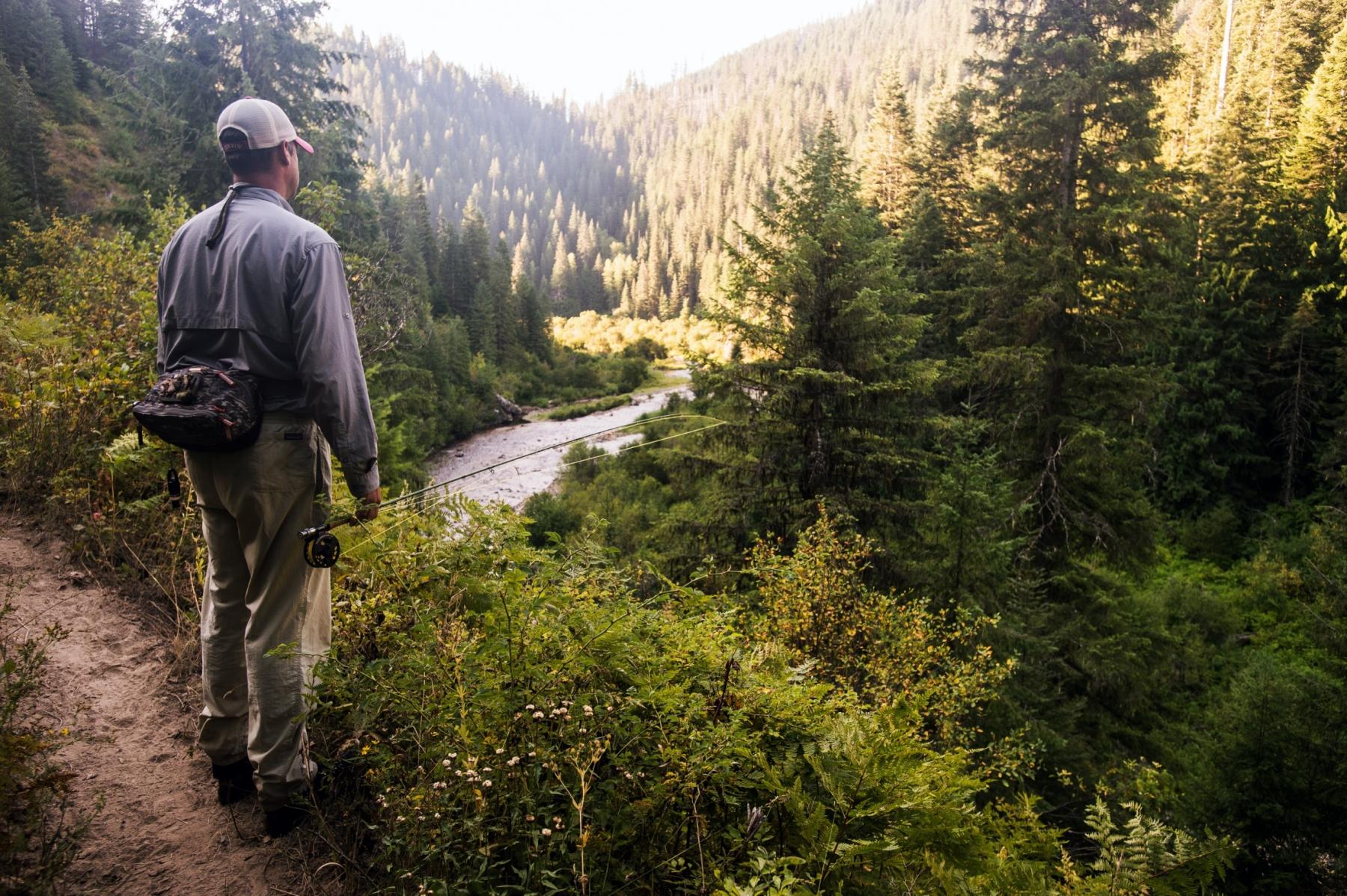 Fly fisher staring out into beautiful river valley