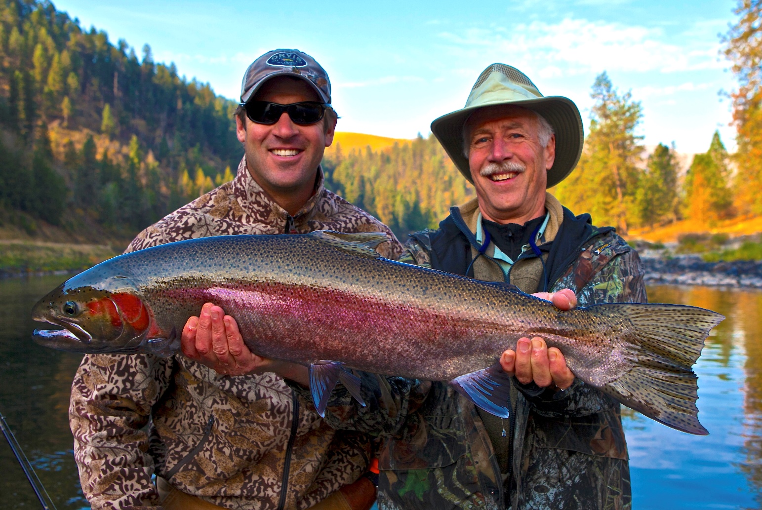 Two men holding a steelhead fish